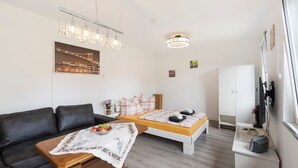 A modern room with a bed, a sofa, a desk, and a TV.