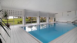 A swimming pool with a tiled floor, large windows, and a view of a green landscape. - Apartment 'Ferienwohnung Alpensicht' with Lake View, Shared Garden and Wi-Fi (Oberteuringen)