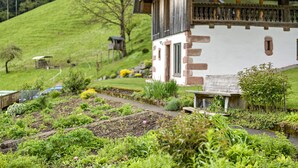 A house with a balcony, a garden with various plants, and a wooden fence. - Metzgerbauernhof Apartment with Shared Terrace, Garden, and Wi-Fi (Wolfach)