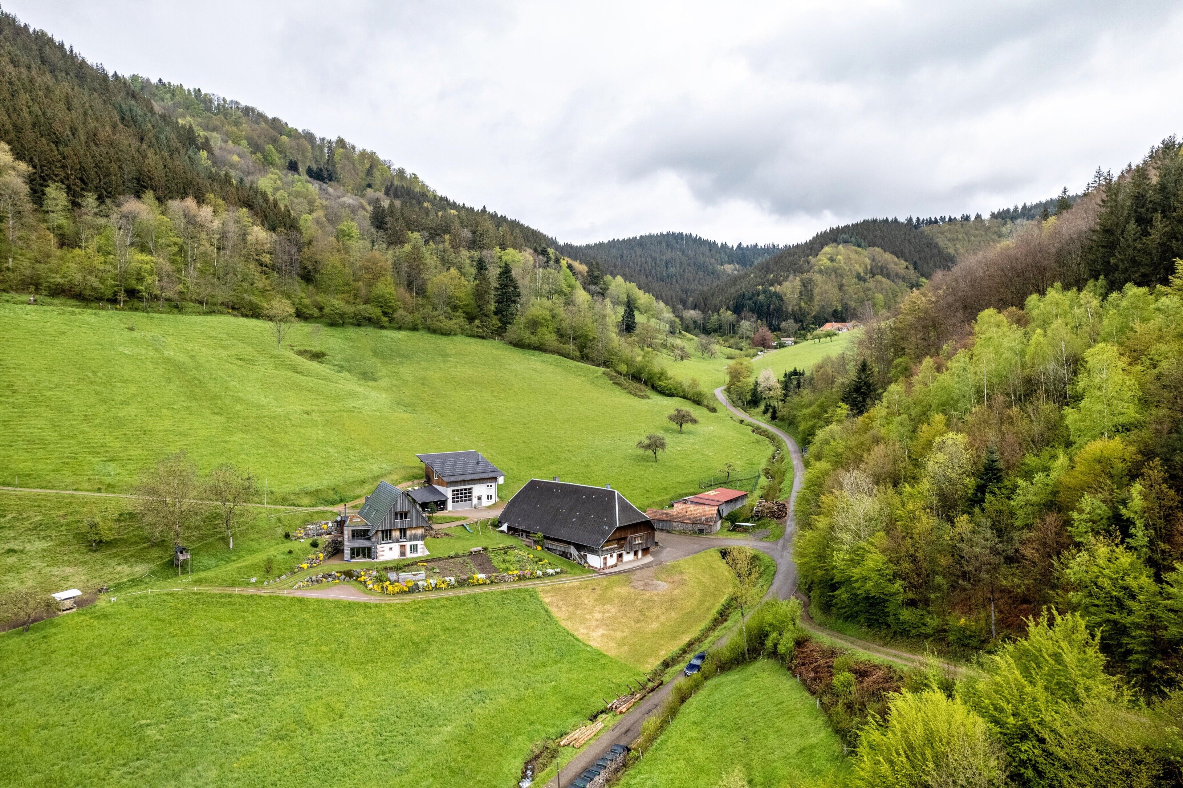 A rural landscape with a house, a barn, and a road.