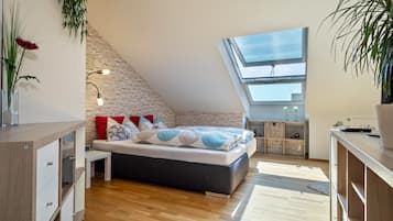 Une chambre moderne avec un plafond en pente, un puits de lumière, un lit avec une literie à motifs, une table de chevet et une commode en bois.