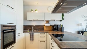 A modern kitchen with white cabinets, a built-in oven, a sink, and a countertop with a backsplash.