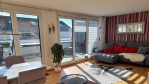 A modern living room with a sofa, a dining table, and a large window.