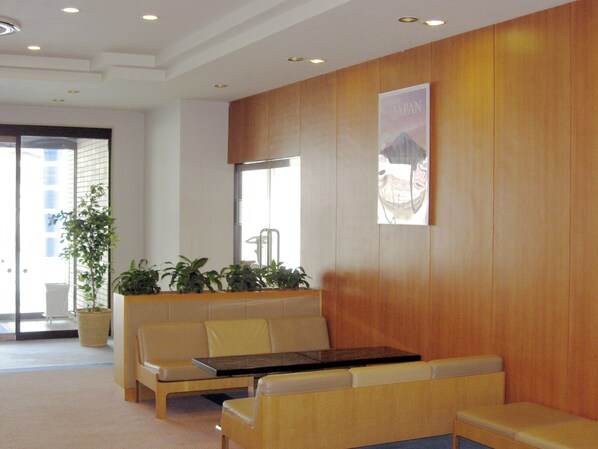 Un área de recepción con un panel de madera, un cartel, un mostrador de recepción y asientos.