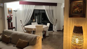 Una sala de estar con sofá, una mesa de comedor con sillas y una lámpara.