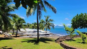Una playa con palmeras, barcos y un cielo azul despejado.
