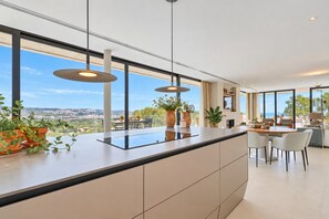 A modern kitchen with a large island, pendant lights, and a view of the city.