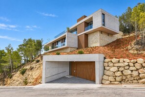 A modern two-story house with a stone facade, a large garage, and a sloped roof.