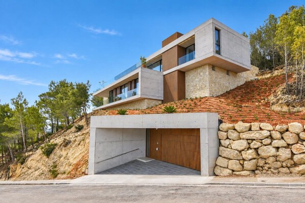 A modern two-story house with a stone facade, a large garage, and a sloped roof.