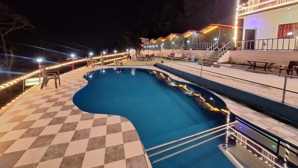 A swimming pool with a checkered floor, surrounded by a railing and a building with a balcony.