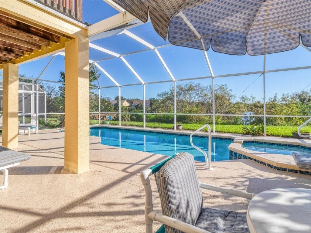 A covered outdoor swimming pool area with a pergola, seating, and a view of the pool.