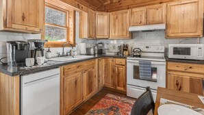 Une cuisine avec des meubles de rangement en bois, une cuisinière, un four à micro-ondes et une machine à café.