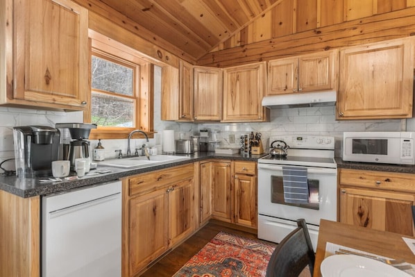 Una cocina con armarios de madera, estufa, microondas y cafetera.
