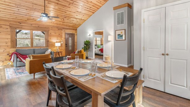 Un coin repas avec une table en bois, dressée pour quatre personnes, entourée de chaises.