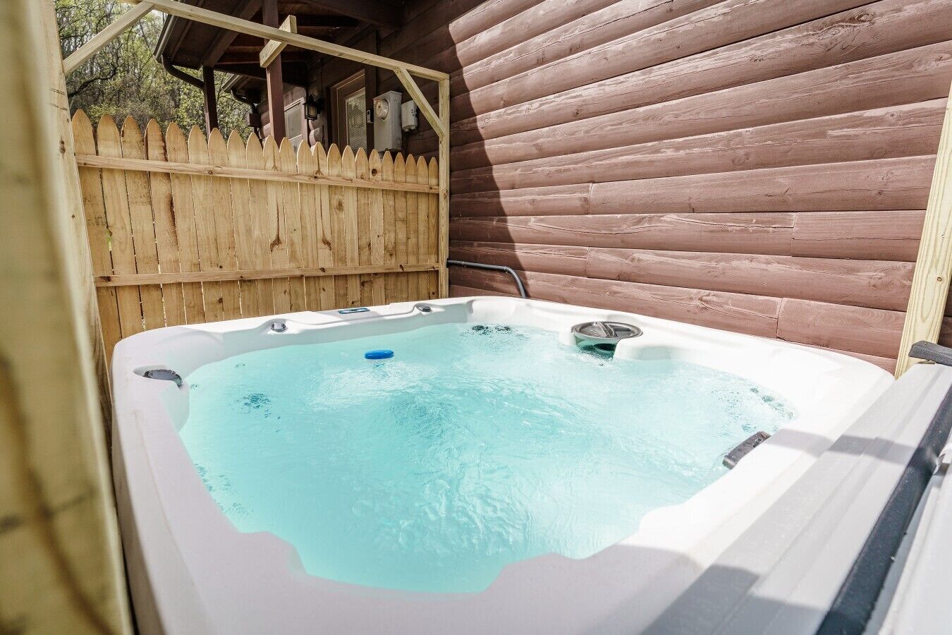 A hot tub in an outdoor setting with wooden walls and a wooden fence.