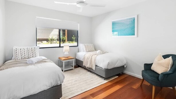 Une chambre avec deux lits, un ventilateur de plafond, une fenêtre avec vue et un fauteuil.