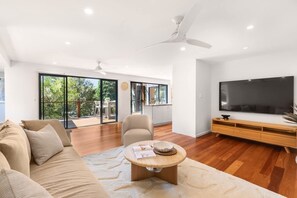 A modern living room with a sofa, a coffee table, a TV, and a ceiling fan.