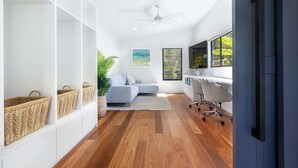 Un salon moderne avec un canapé, un bureau et une chaise. On y trouve des paniers sur des étagères et une plante.