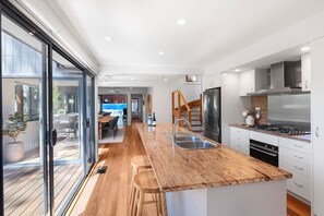 A modern kitchen with a central island, stainless steel appliances, and a sliding glass door leading to an outdoor area.