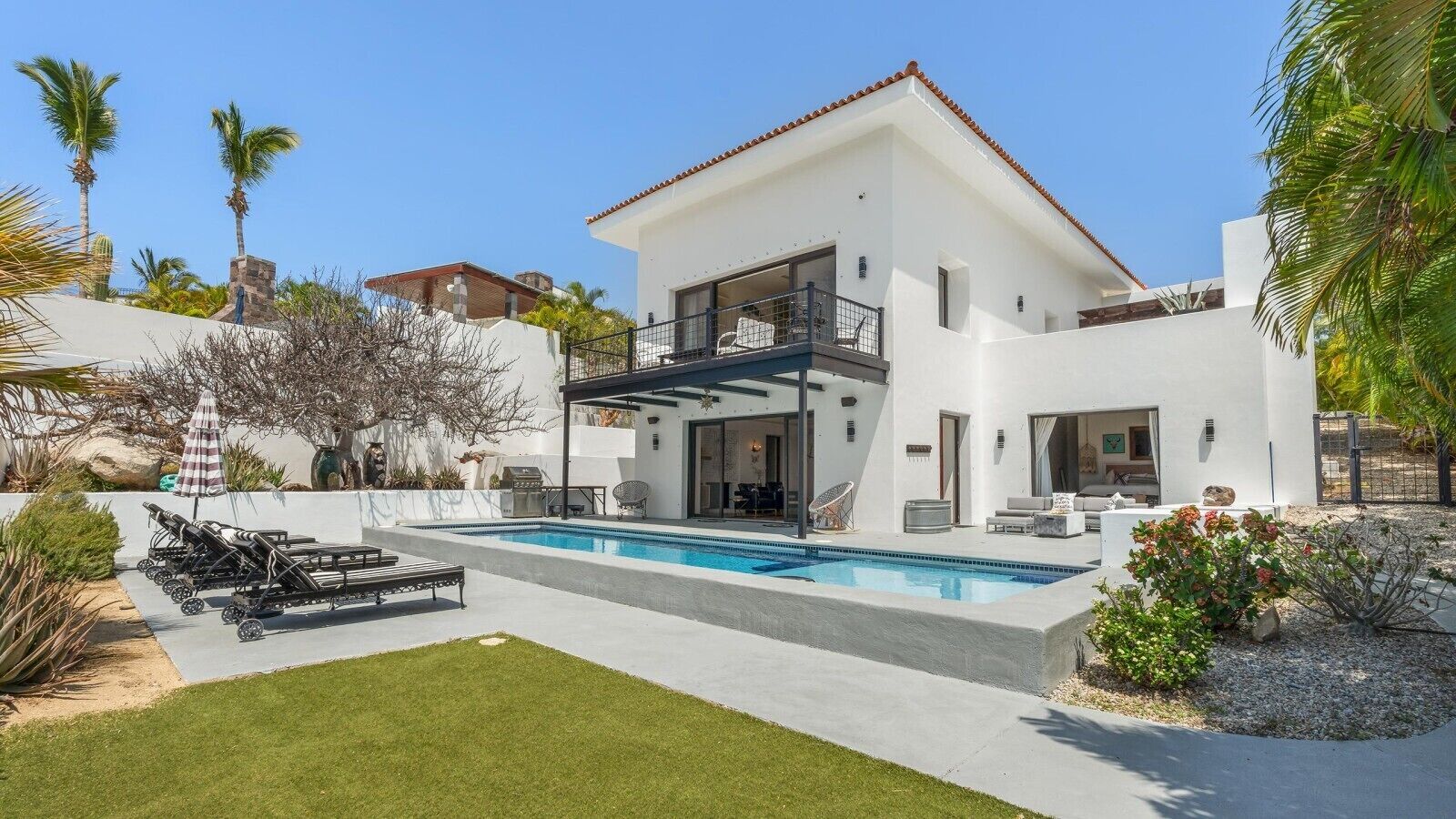 A modern two-story house with a swimming pool, outdoor seating, and a well-maintained garden.