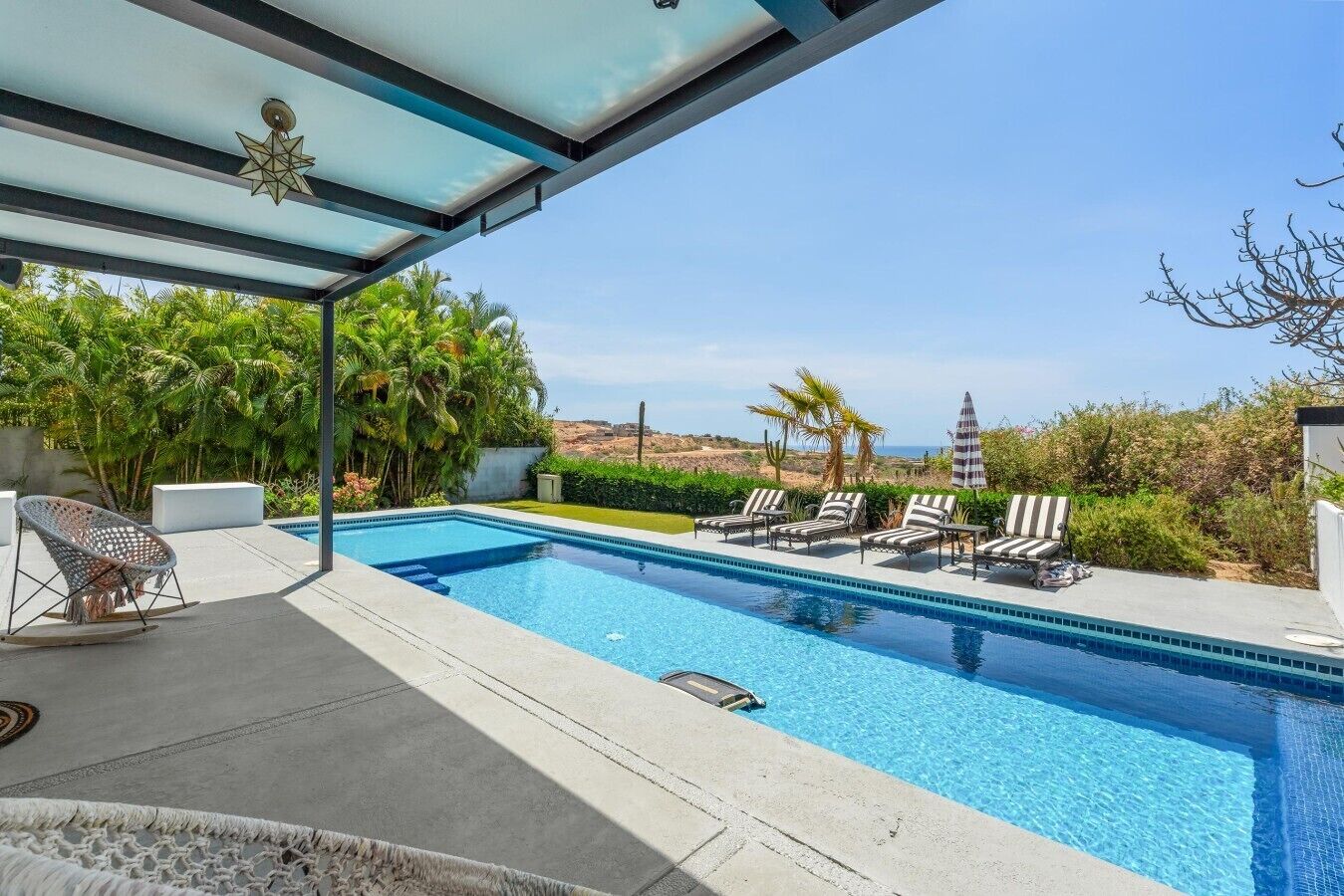 A swimming pool with lounge chairs and a covered seating area.