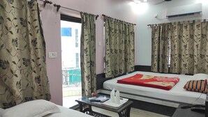 A hotel room with two beds, a small table with a remote control, a phone, and a window with curtains. - Hotel Sea Sand (Kanthi)
