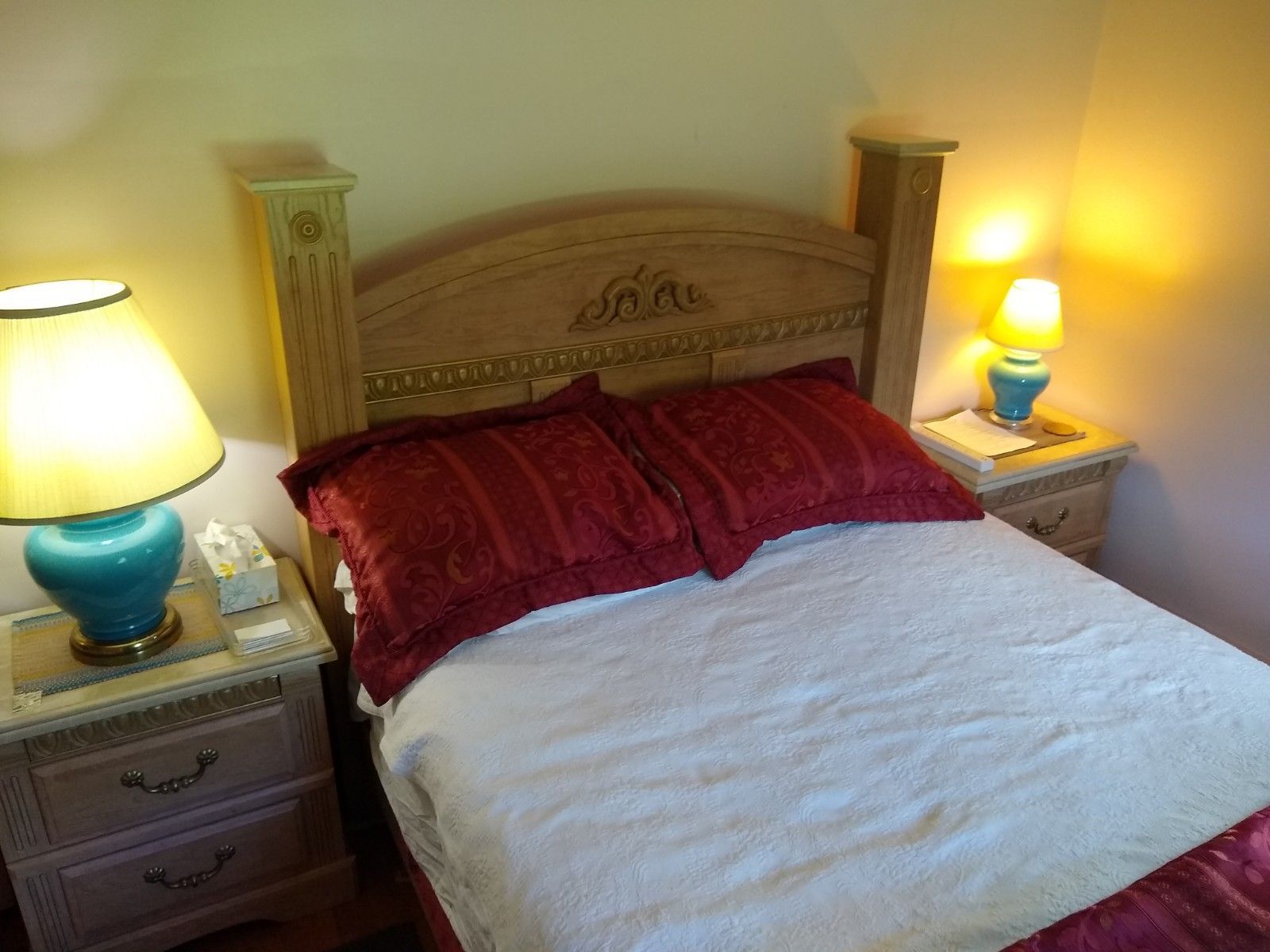 A bed with a headboard, two bedside tables with lamps, and a nightstand with drawers.
