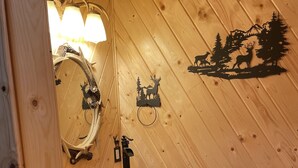 A rustic bathroom with a wooden barrel sink, a mirror, and a wall decal of deer and trees. - NEW BRAUNFELS - DEER HAVEN CABIN 
 (New Braunfels)
