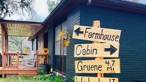 A wooden signpost with directions to various locations including Farmhouse, Cabin, Gruene, Wimberley, Houston, and San Antonio. - NEW BRAUNFELS - DEER HAVEN CABIN 
 (New Braunfels)