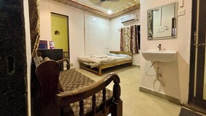 A bedroom with a bed, a bedside table, a chair, a bedside lamp, a mirror, and a window. - Sun And Sand Holiday Home (Malvan)
