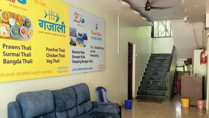 A hotel lobby with a blue sofa, a staircase, and various posters advertising local attractions and dining options. - Sun And Sand Holiday Home (Malvan)