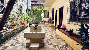 A courtyard with a tiled floor, potted plants, and a bench. - Sun And Sand Holiday Home (Malvan)