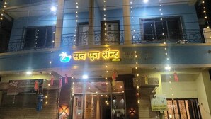 A multi-story building with a sign in a local language, balconies, and string lights. - Sun And Sand Holiday Home (Malvan)