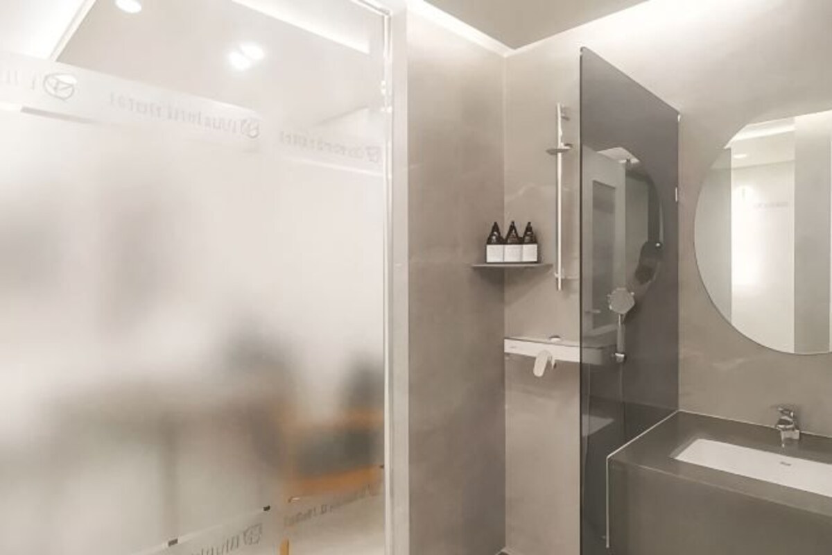 Een moderne badkamer met een douchecabine van glas, een grote spiegel en een wastafelmeubel met een wastafel.