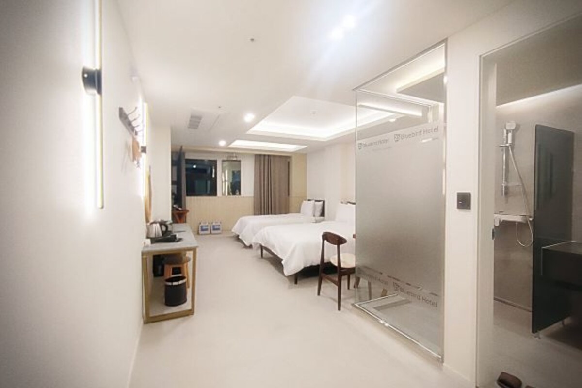 Een hotelkamer met een bed, een bureau, een stoel en een douche.
