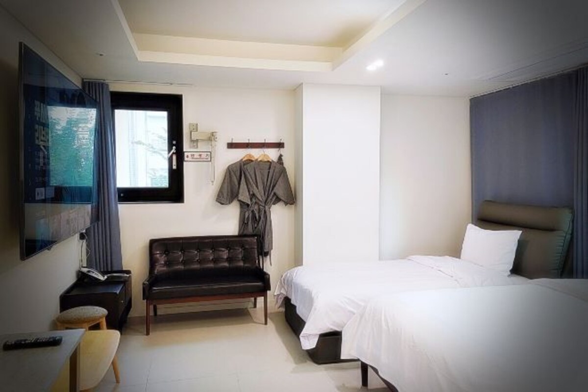 Een hotelkamer met een bed, een bank, een televisie en een raam.