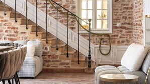 A staircase with a stone wall, a sofa, and a table in a room with a herringbone floor pattern.