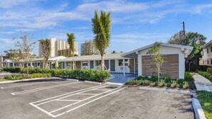A hotel with a parking lot, modern buildings, and palm trees. - Pelican Studio w/ Private Patio • Pompano (Pompano Beach)