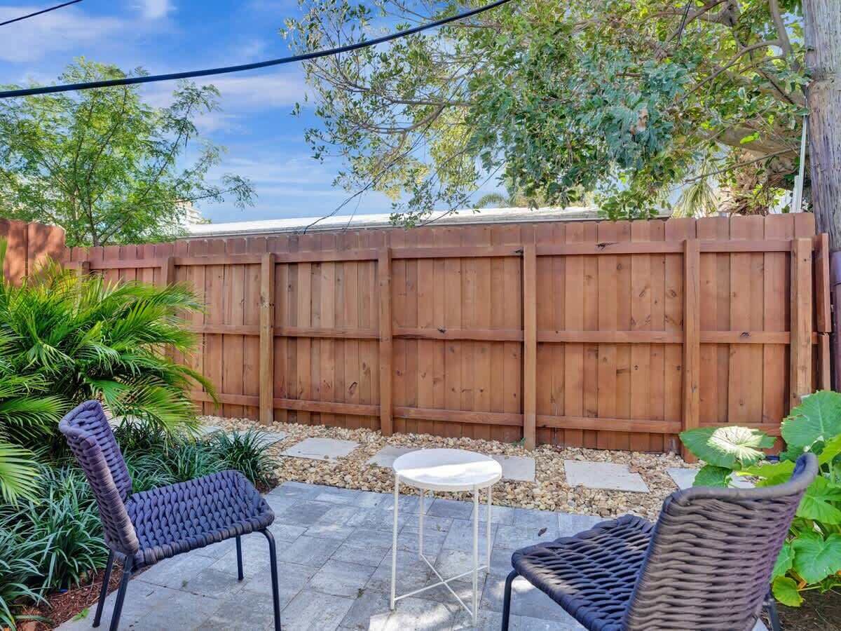 A patio with two wicker chairs, a small round table, and a wooden fence.