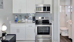 Una cocina moderna con gabinetes blancos, un microondas integrado, una estufa y un horno.