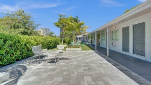 A patio with outdoor furniture, a swimming pool, and a building with large windows and doors.