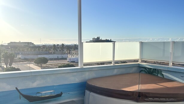 Uma banheira de hidromassagem no terraço com vista para o mar e edifícios.