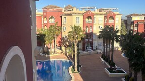 Pátio de hotel com piscina, palmeiras e edifícios de vários andares com varandas.