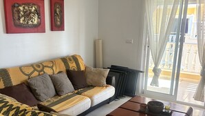 Uma sala de estar com sofá, mesa de centro e janela com cortinas.