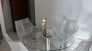 Uma mesa de vidro moderna com quatro cadeiras, um vaso com flores e uma porta com o número 142.