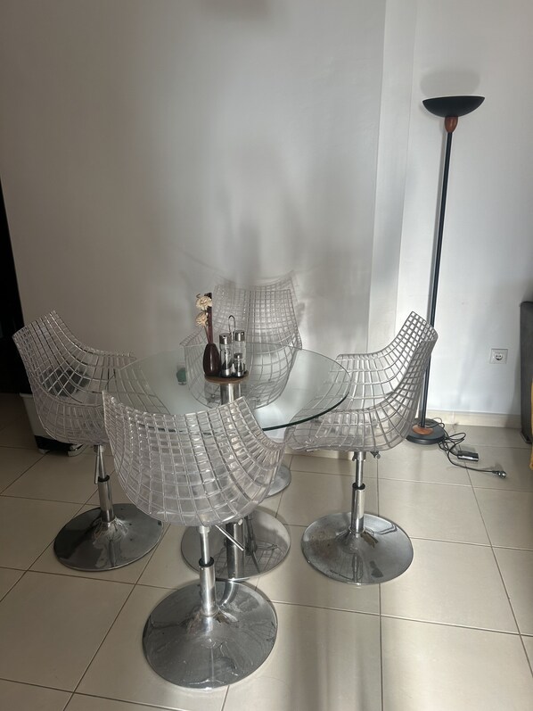 Een eetruimte met een ronde tafel en vier stoelen met een draadframe.