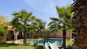A backyard with a swimming pool, palm trees, and outdoor furniture. -  Relax in the beauty of a saffron farm in the foothills of Atlas Mountains  (Marrakech)