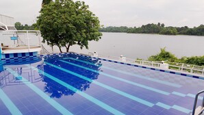 A swimming pool with blue tiles and a tree in the background. - Rangadip Resort Rangamati (Rangamati Sadar)