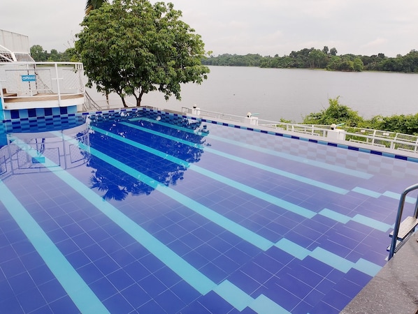 A swimming pool with blue tiles and a tree in the background.