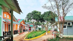 A row of colorful houses with a dirt path and a garden area. - Rangadip Resort Rangamati (Rangamati Sadar)